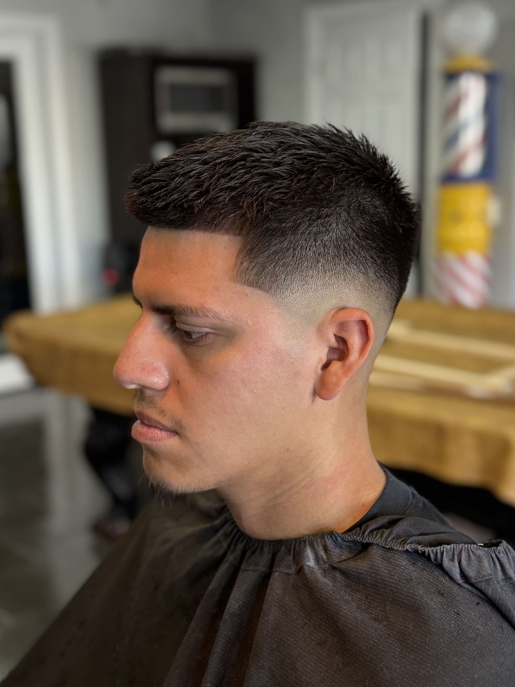 Low skin fade with textured crop and sharp line-up.