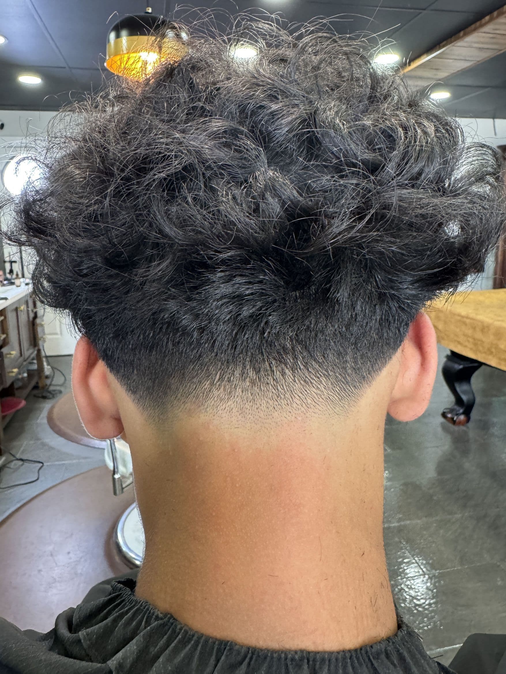 Low drop bald fade with natural curls on top.