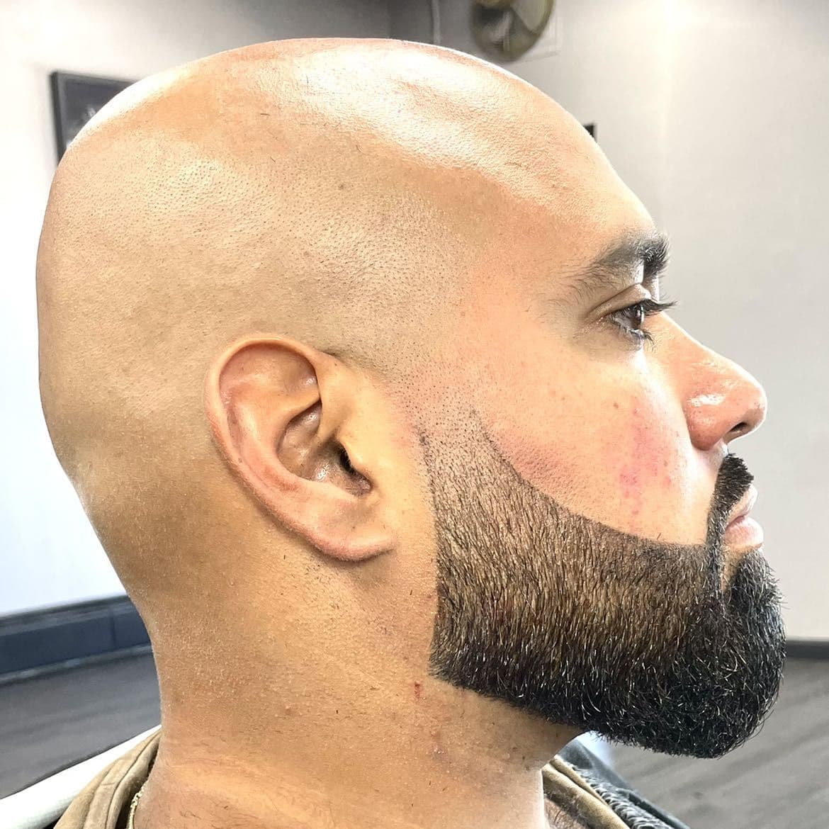 Clean bald shave with sharp beard shape-up and sculpt.