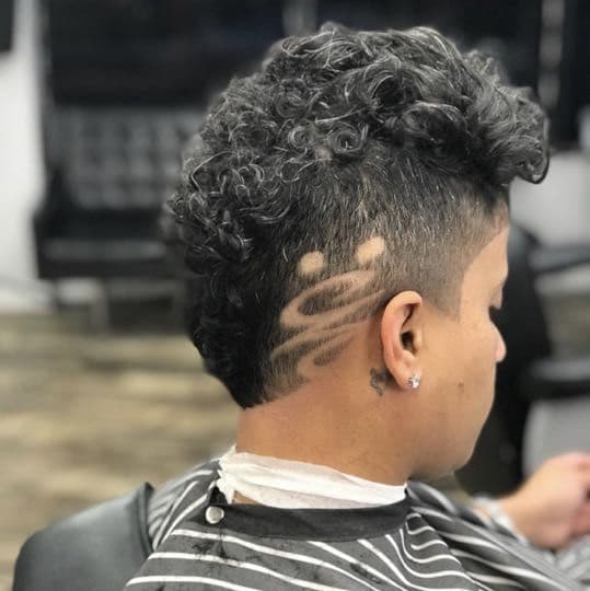Curly mohawk with burst fade and hair design detail.