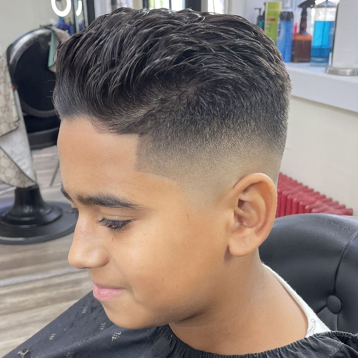 Kids comb-over slick back with a mid fade and line-up.