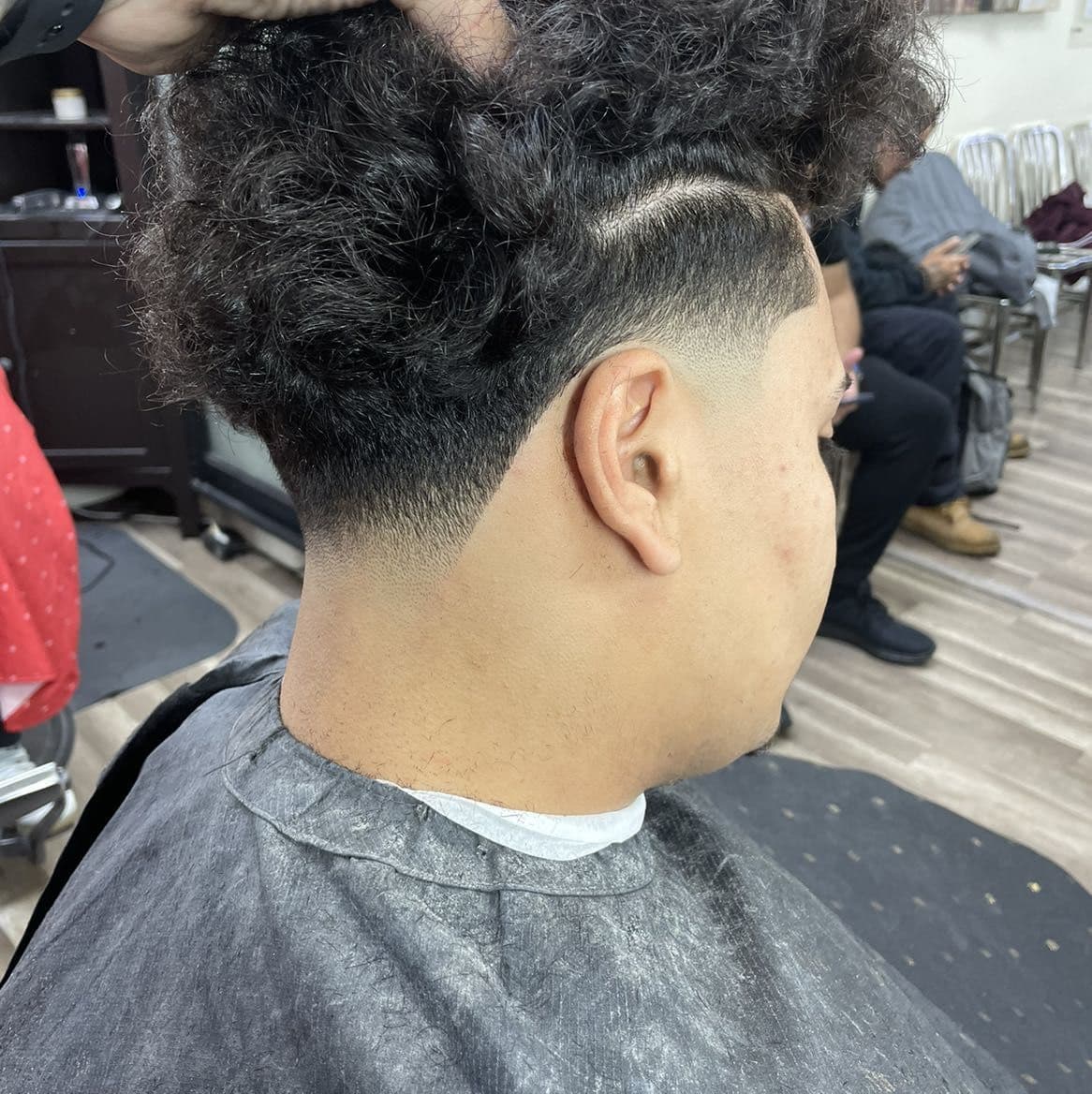 Curly top with low taper fade, hard part, and line-up.